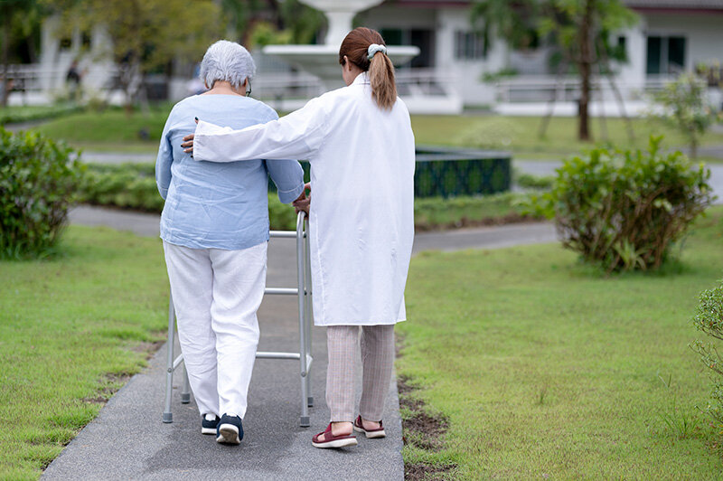 Mujer pasea con una profesional de una residencia de mayores (Foto: envato)